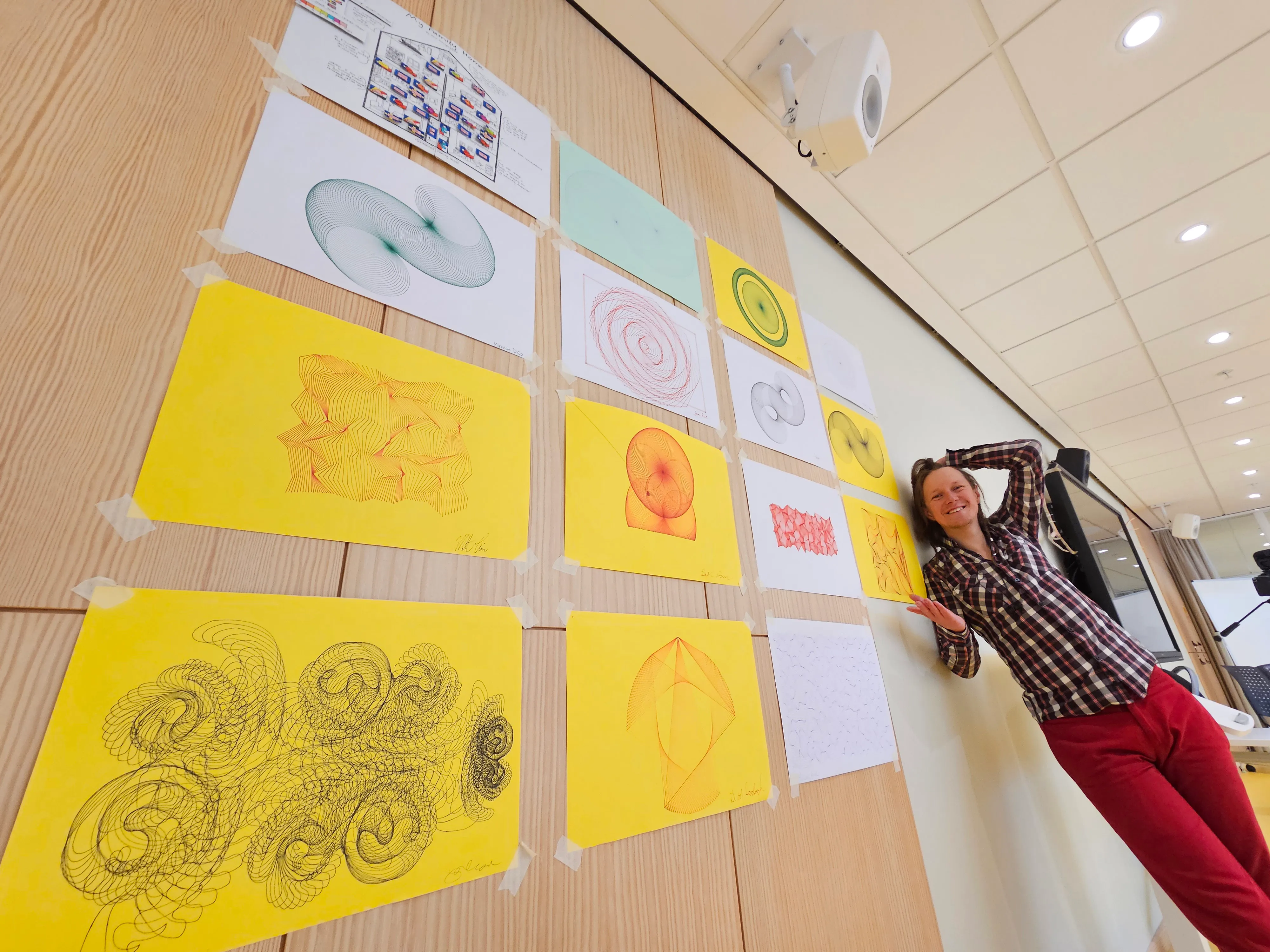Angie Hjort beside a wall of student generative drawings.